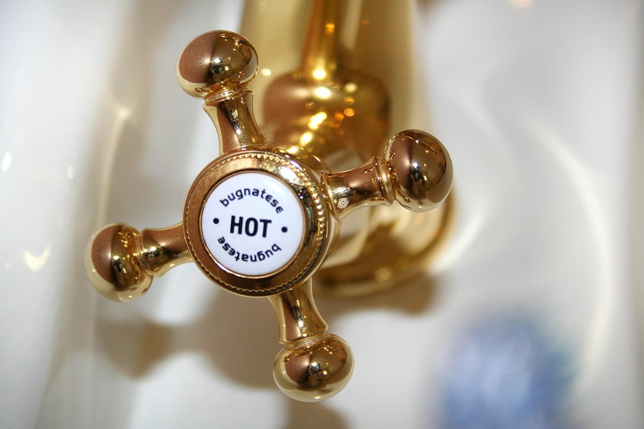 A brass cross-head tap marked HOT on a white basin